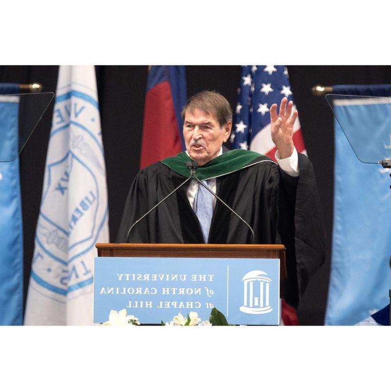 Dr. Shelley Earp wearing black regalia and speaking into a microphone at U.N.C. Chapel Hill's Winter Commencement.