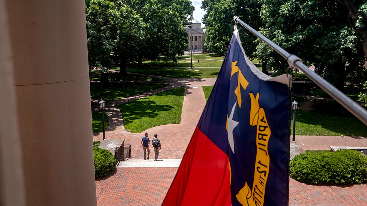 North Carolina flag hangs from South Building looking out into the quad.