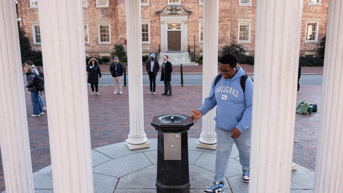 Student approaching the fountain of the Old Well for his 'first sip' on the first day of classes of the spring semester at U.N.C Chapel Hill.